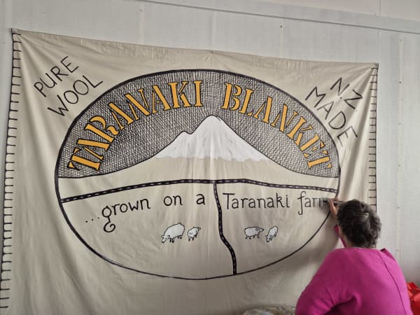 The Taranaki Blanket logo features a central image of the region's maunga, the main highways which surround it and grazing sheep.