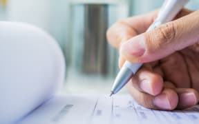 Hand with pen over application form on blure water glass background