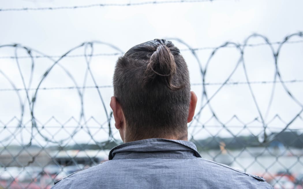 A prisoner stands behind a security fence at Paremoremo.