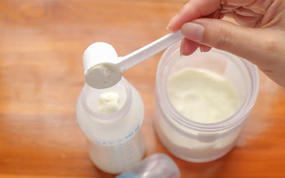 putting powdered milk into a baby bottle
