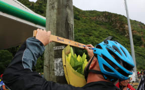 A cyclist writes on the tribute cross on the side of the Hutt Road.
