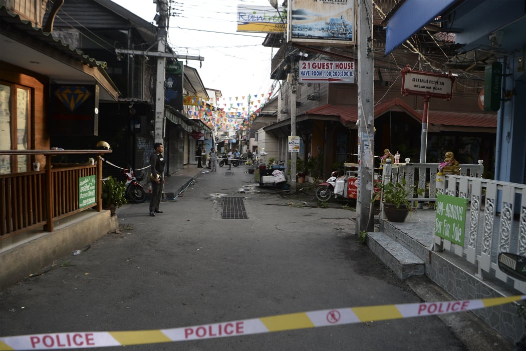 A police officer, left, stands guard where a small bomb exploded in Hua Hin on 12 August.