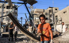 A boy inspects the rubble of a collapsed building in the aftermath of Israeli bombardment at the Jaouni school run by the UN Relief and Works Agency for Palestine Refugees (UNRWA) in Nuseirat in the central Gaza Strip on July 6, 2024 amid the ongoing conflict in the Palestinian territory between Israel and Hamas. (Photo by Eyad BABA / AFP)