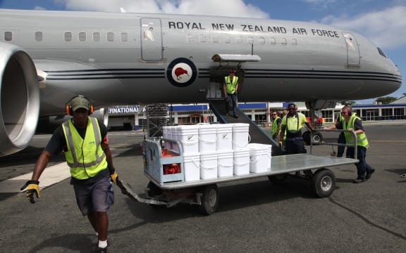 A baggage handler at Bauerfield Airport, Port Vila, Vanuatu, pulls a trolley containing water containers from a Boeing 757 to a waiting RNZAF C130 Hercules. The Boeing arrived at Port Vila with 11 tonnes of relief supplies for Ambae Island.