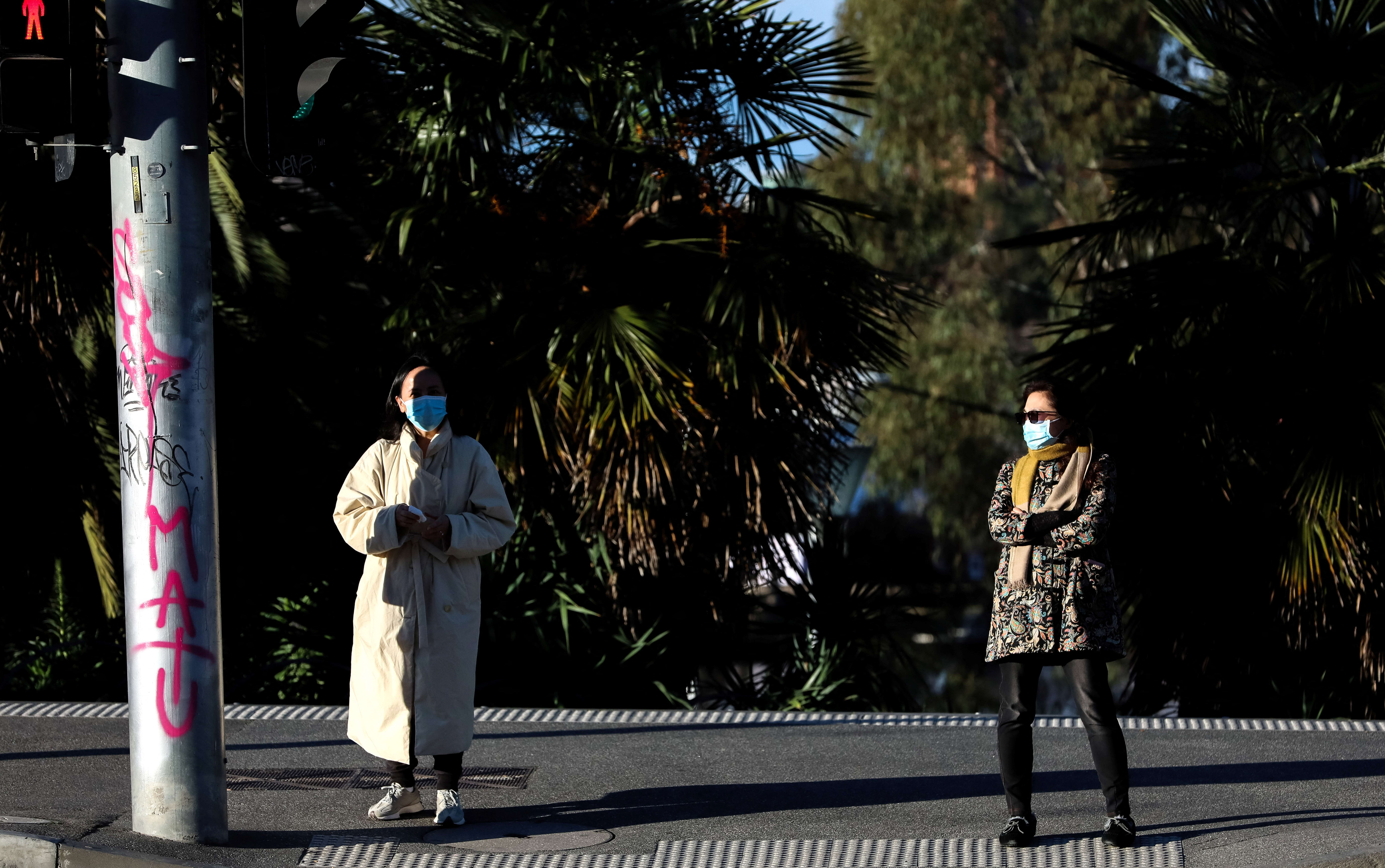 Pedestrians wearing masks and maintaining distance at a traffic light in the Southbank area of Melbourne, 16 July 2021.