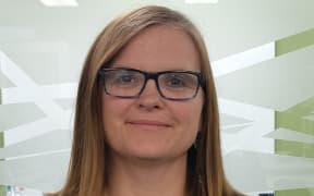 This is a head and shoulders shot of Kali Mercier. She is wearing teal glasses which match the colour of her top.