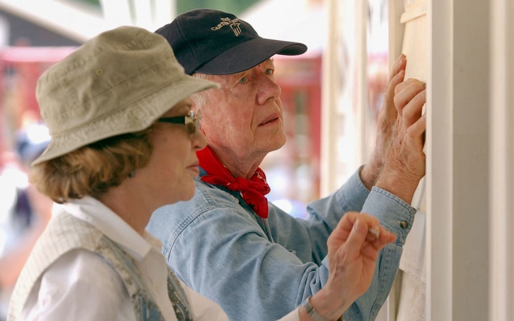 Former US president Jimmy Carter (R) and his wife Rosalyn attach siding to the front of a Habitat for Humanity home being built 10 June, 2003 in LaGrange, Georgia. More than 90 homes are being built in LaGrange, Valdosta, Georgia  and Anniston, Alabama by volunteers as part of Habitat for Humanity International's Jimmy Carter Work Project 2003.  (Erik S. Lesser/Getty Images/AFP) -FOR NEWSPAPER AND TV USE ONLY- (Photo by Erik S. Lesser / Getty Images North America / Getty Images via AFP)