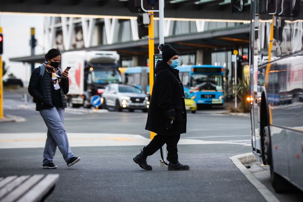 Commuters wearning masks board a bus Manukau