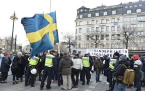 Police talk to participants of a movement calling itself "The People's Demonstration".
Dozens of masked men believed to belong to neo-Nazi gangs carried out assaults on migrants in Stockholm overnight.