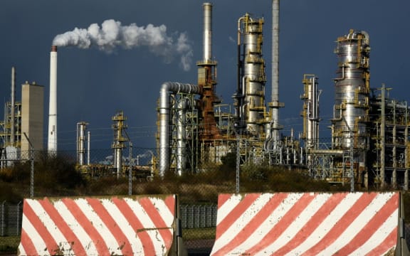 Barriers stand in front of a gate of the facilities of TotalEnergies Raffinerie Mitteldeutschland GmbH in Leuna, over which black clouds are drifting.