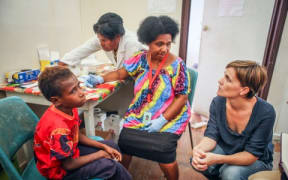 Dr Leanne Robinson (far right) with patient Jonathan (far left), who is being tested for malaria by Nursing Officer Kay Kose (second from left) and microscopist Barbara Sambre (second from right).