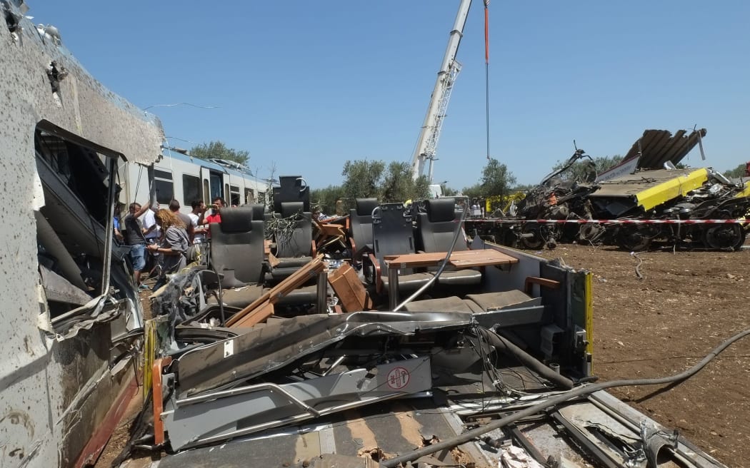 Officials inspect the train crash site on July 13, 2016 near Corato, in the southern Italian region of Puglia as rescuers searched for missing bodies from the wreckage of a head-on collision that claimed at least 25 lives.