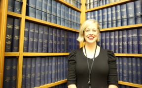 Claire Gilray stands in front of bound copies of Hansard