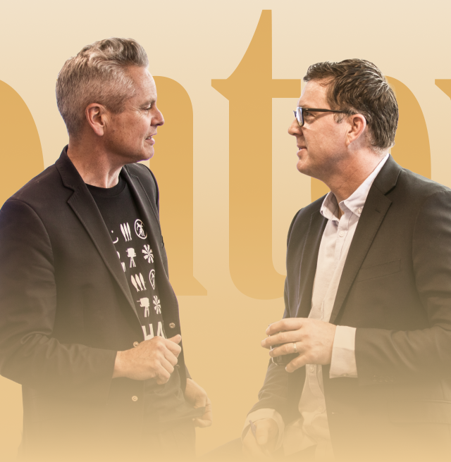Two men converse intently way in front of large letters that read "Context"