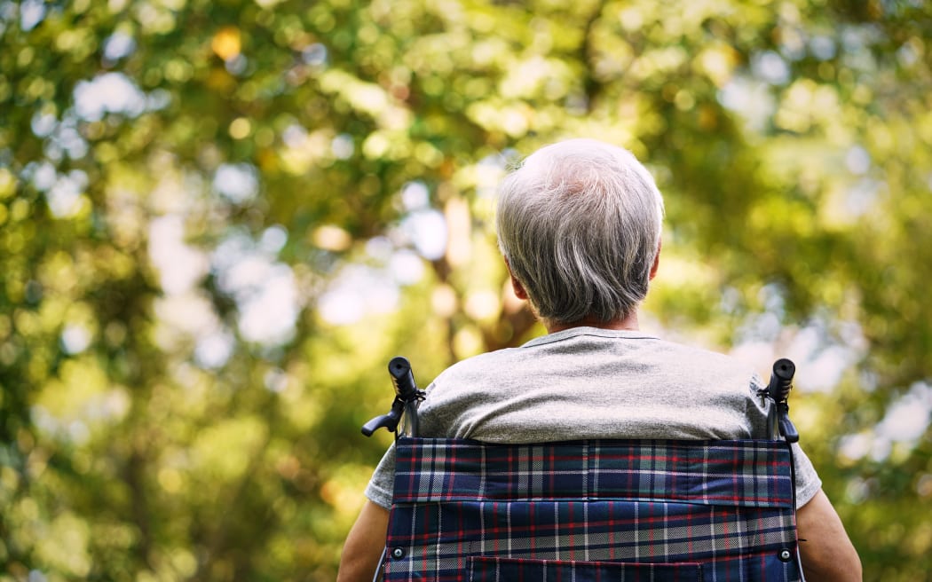 rear view of a senior man sitting in a wheelchair looking up