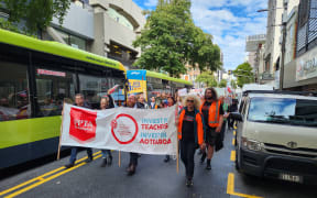 Striking teachers March through Wellington on 10 May, 2023. PPTA acting president Chris Abercrombie at centre of banner.