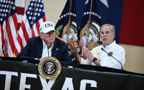 US President Donald Trump (L) listens to Texas Governor Greg Abbott speak during a meeting with local officials and first responders in Kerrville, Texas, on July 11, 2025, following devastating flooding that ocurred in the area over the July 4 weekend. At least 120 people are dead and more than 170 still missing, following July 4 holiday weekend floods that ravaged the central Texas Hill Country -- including a river bank cluttered with children's summer camp cabins. (Photo by Brendan SMIALOWSKI / AFP)