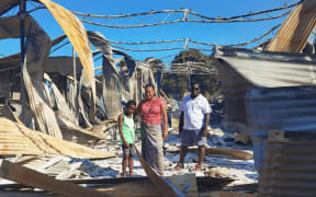 Namoi Kaluae with her husband and son amid what's left of their 10-year-old business.