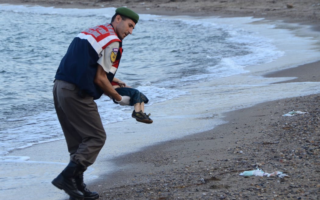 A Turkish police officer carries the 3-year-old's dead body off the beach in Bodrum, southern Turkey.