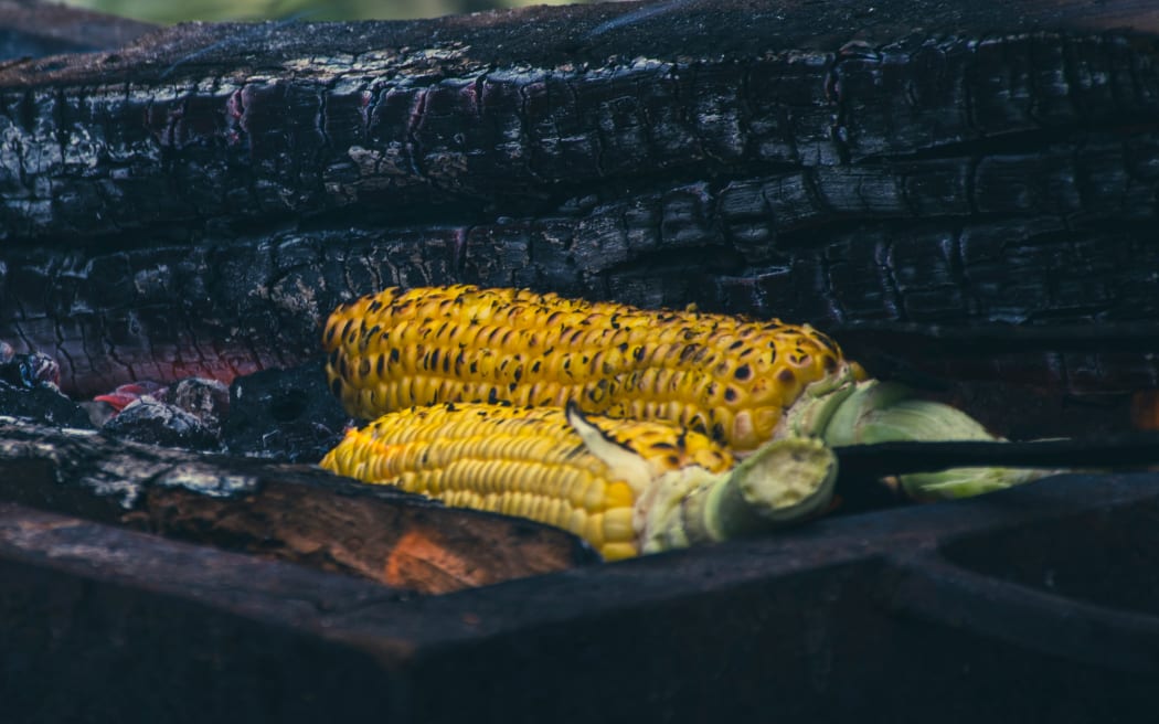 Bhanu's husband grills coal-charred corn as she shares her story.