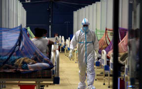 A doctor walks past Covid-19 patients at a makeshift facility created inside a sports complex, amidst the spread of coronavirus cases, in New Delhi, India on May 13, 2021.