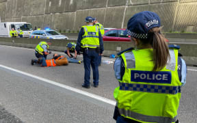Police removing protesters who had glued themselves to the road surface in the southbound lane of SH1 just before Wellington's Terrace Tunnel.