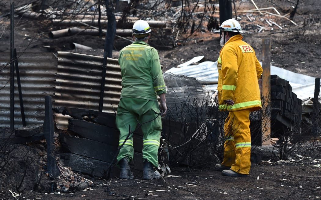 Emergency services workers inspect fire damaged buildings at Separation Creek in the Otway Ranges south of Melbourne.
