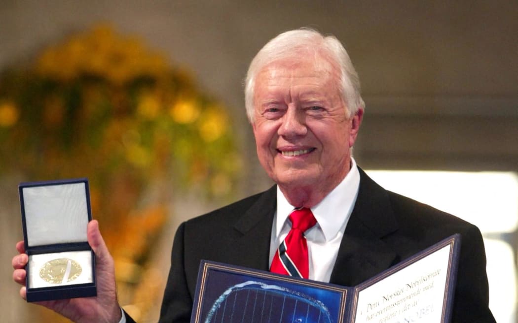 Former US president Jimmy Carter smiles after receiving the 2002 Nobel Peace Prize during a ceremony in the Oslo City Hall 10 December 2002. (Photo by POOL / AFP)