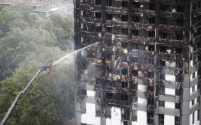 An automated hose sprays water onto Grenfell Tower.