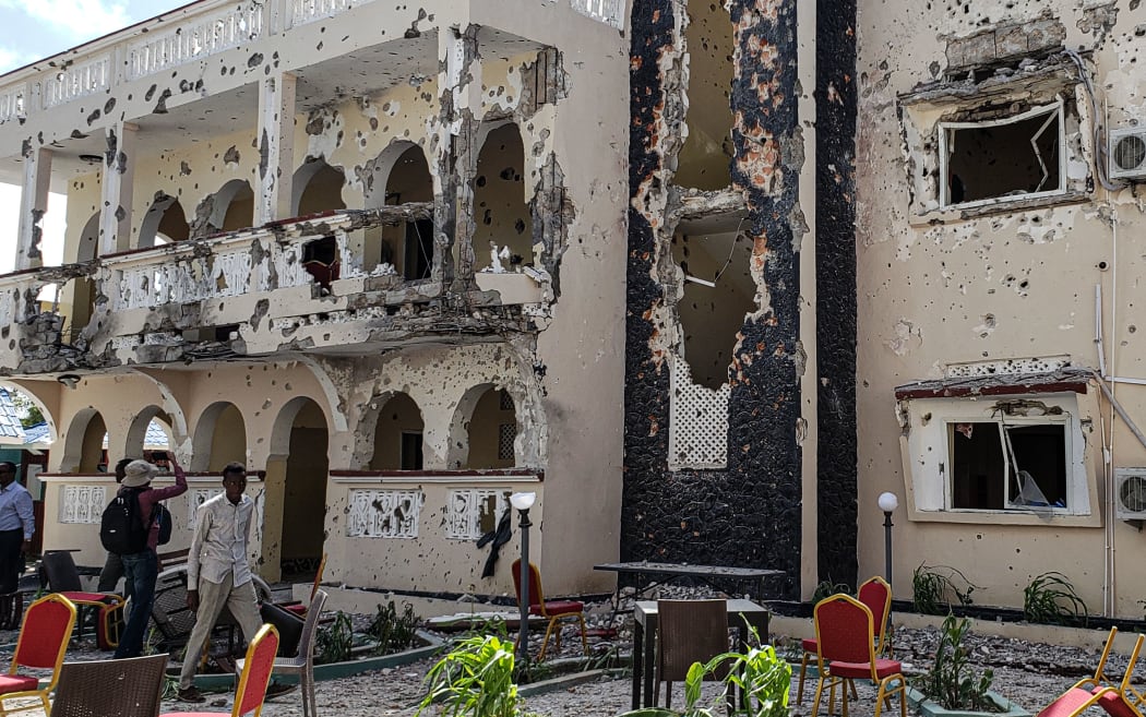 A man passes in front of the rubbles of the popular Medina hotel of Kismayo on July 13, 2019, a day after at least 26 people, including several foreigners, were killed and 56 injured in a suicide bomb and gun attack claimed by Al-Shabaab militants.