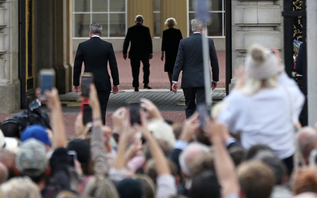 King Charles III and Camilla, Queen Consort (C) walk into Buckingham Palace after greeting the crowd and looking at floral tributes, in London, a day after Queen Elizabeth II died.