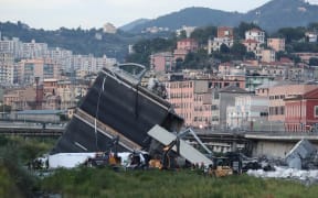 Rescuers inspect the rubble and wreckages by the Morandi motorway bridge after a section collapsed in Genoa.