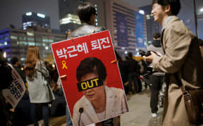 A protester in Seoul holds a sign calling for the resignation of President Park Geun-hye.