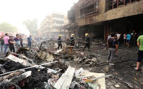 Iraqis at the site of the suicide car bombing in Baghdad's central Karrada district.