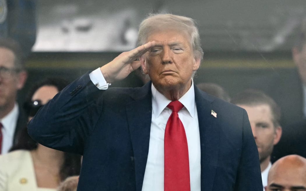 US President Donald Trump stands and salutes during the Army 250th Anniversary Parade from the Ellipse in Washington, DC.