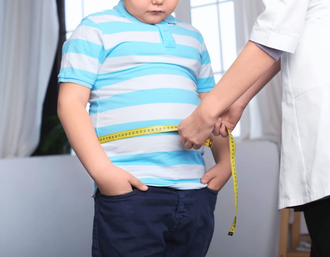 A doctor measuring a boy's waist.