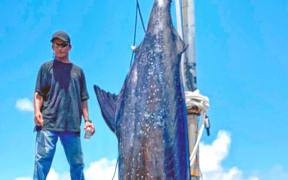 Marshall Islands angler Bwiji Aliven stands on the dock next to his mammoth marlin catch, which weighed in at 429kg.