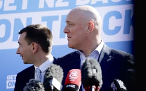 National Party leader Christopher Luxon and MP Simeon Brown react to heckler during press conference in Auckland on 28 August, 2023.
