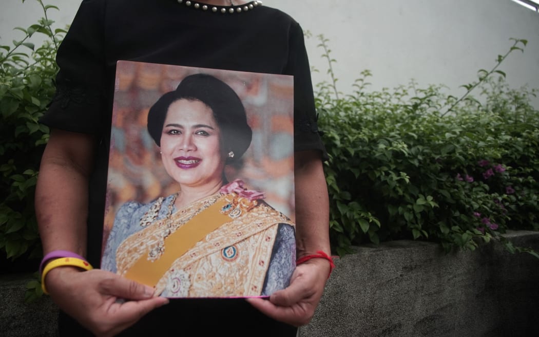 A woman holds photographs of Thailand's Queen Mother Sirikit as people react following the announcement of her death outside King Chulalongkorn Memorial Hospital in Bangkok, Thailand, on October 25, 2025. Queen Sirikit of Thailand passes away. According to the official announcement by the Bureau of the Royal Household, she dies at 21:21 (local time) on Friday, October 24, 2025, at King Chulalongkorn Memorial Hospital in Bangkok at the age of 93. (Photo by Piti Anchaleesahakorn/NurPhoto) (Photo by Piti Anchaleesahakorn / NurPhoto via AFP)
