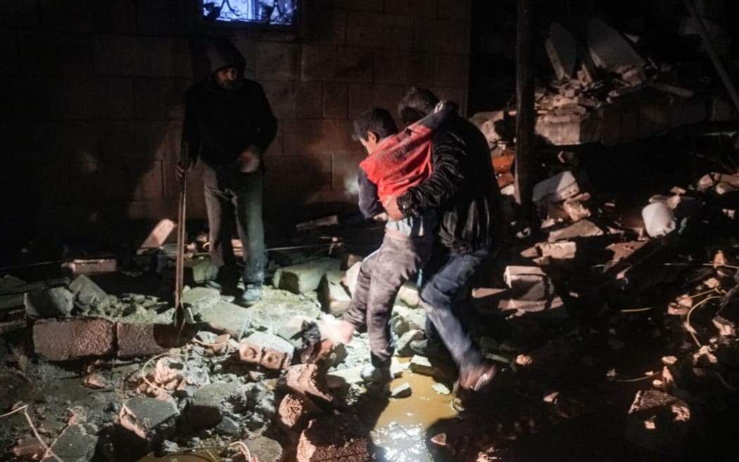 A man carries away an injured child following an earthquake in the town of Jandaris, in the countryside of Syria's northwestern city of Afrin in the rebel-held part of Aleppo province, early on February 6, 2023. - At least 42 have been reportedly killed in north Syria after a 7.8-magnitude earthquake that originated in Turkey and was felt across neighbouring countries. (Photo by Rami al SAYED / AFP)