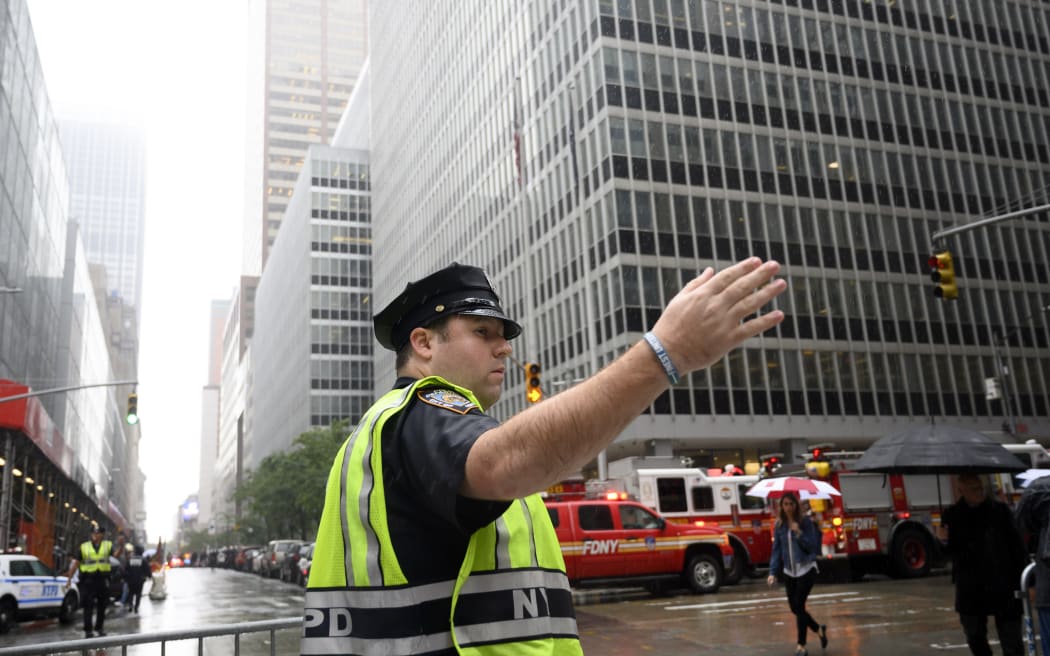 A policeman standing near fire trucks after a helicopter crash-landed on top of a building in midtown Manhattan in New York on 10 June 2019.
