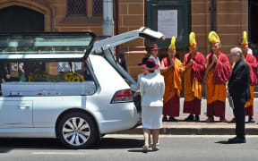 Buddhist monks pray as the coffin of Sydney siege victim Tori Johnson is placed in a hearse after his funeral.