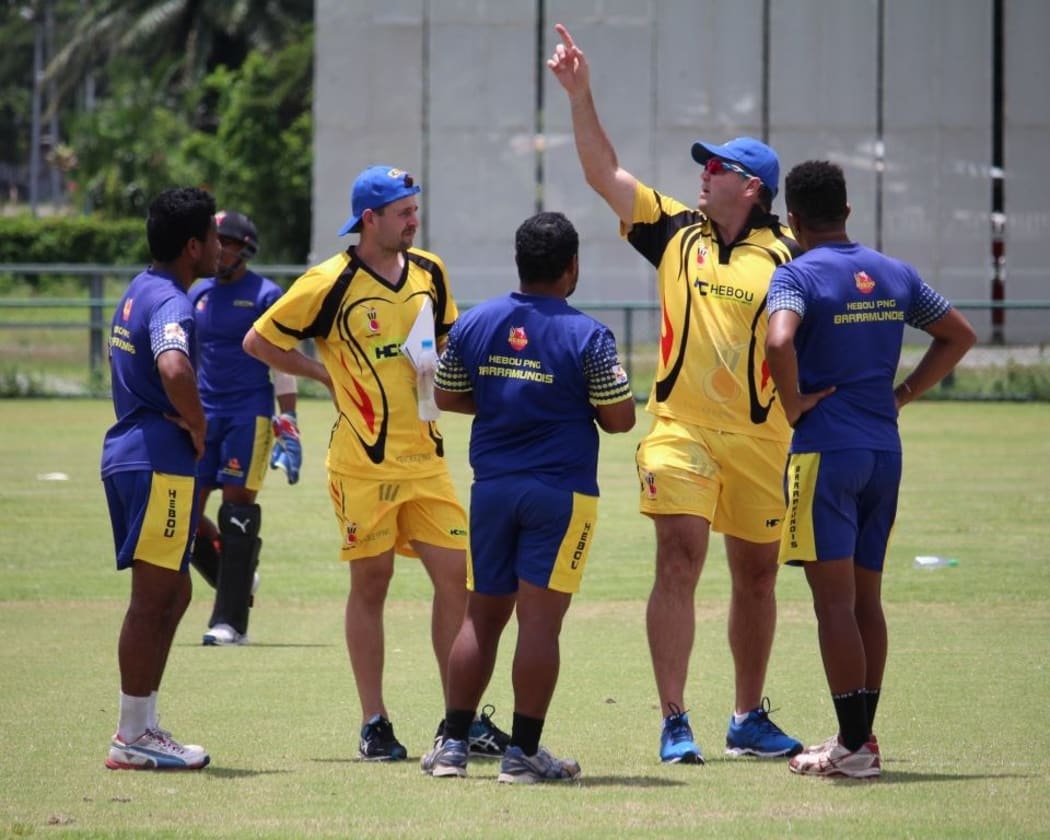 Liam O'Connor (in yellow) watches on with members of the Barramundis team as head coach Joe Dawes (2R) makes a point.