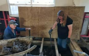 Natasha Tanner (right) removing silt from under floorboards.