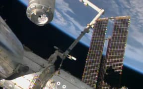 The Cygnus cargo ship (top left) being captured by a robotic arm and brought to the International Space Station on Sunday.