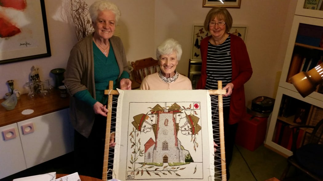 Hillary Brooks, Anne Chipperfield and Carol Lewis stand with their panel, Panel 19 of the Mt. Felix Tapestry