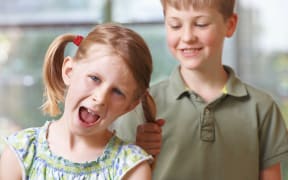 A photo of a boy pulling his sister's hair
