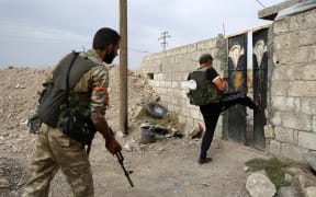 Turkey-backed Syrian fighters break open  the front door of a house at a postition that they are holding in the Syrian border town of Ras al-Ain on October 19, 2019.