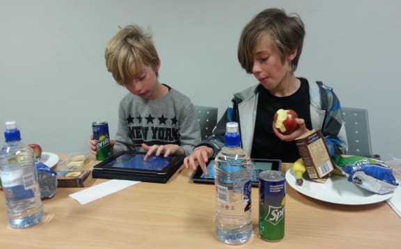 A photo of Johan and Thurston Vogels playing on screens while eating