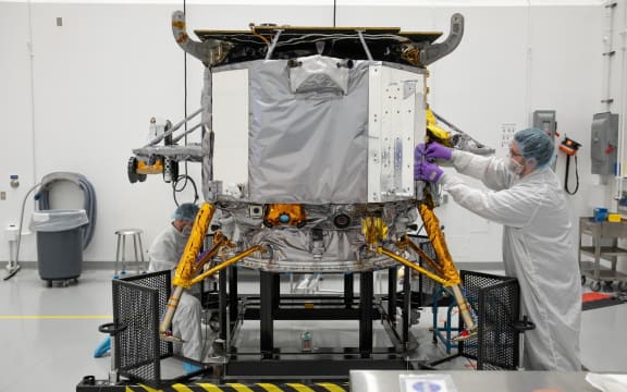Un miembro del equipo Astrobotic de la NASA instala la calcomanía de la NASA en el módulo de aterrizaje lunar Peregrine de Astrobotic el 14 de noviembre en el Centro de Operaciones Espaciales Astrotech en Florida.